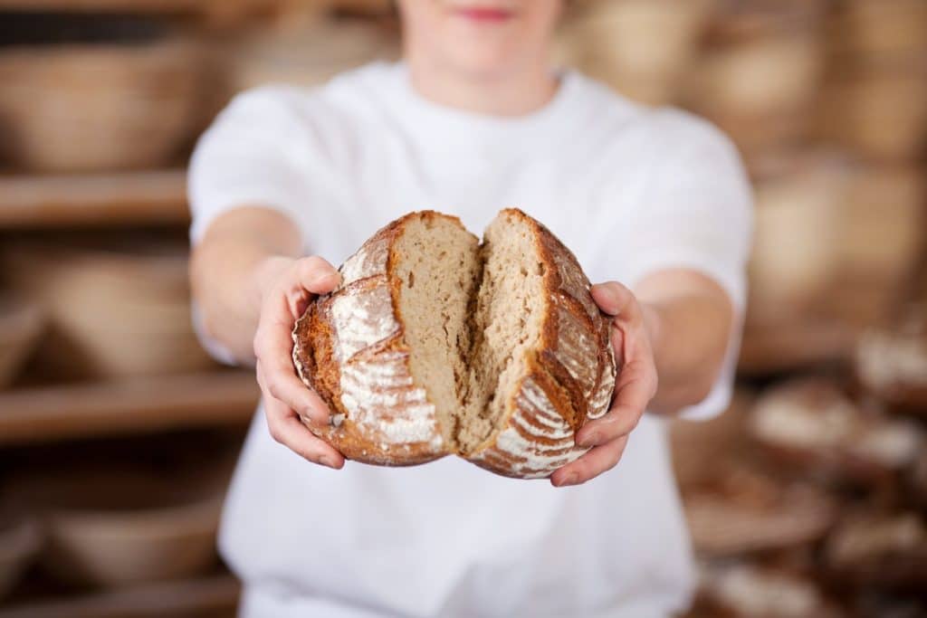 Bäcker zeigt frisch gebackenes Brot